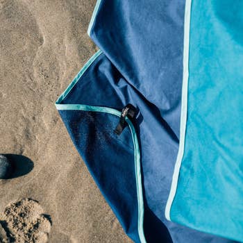 Blue beach towel on the sand with visible brand tag
