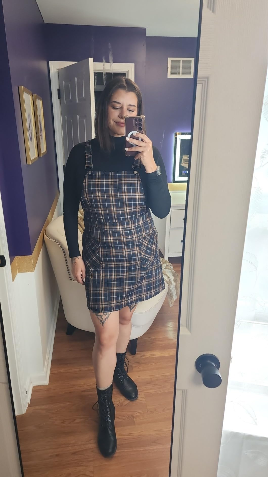 Person smiling successful  reflector  selfie, wearing a plaid pinafore formal  implicit    a achromatic  turtleneck with lace-up boots