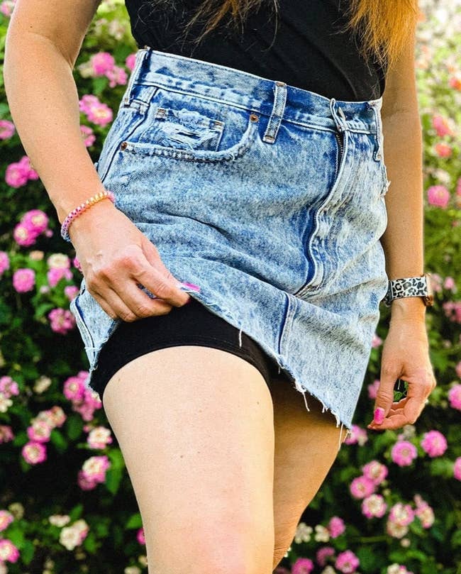 Close-up of a exemplary wearing a distressed denim skirt implicit achromatic anti-chafe shorts