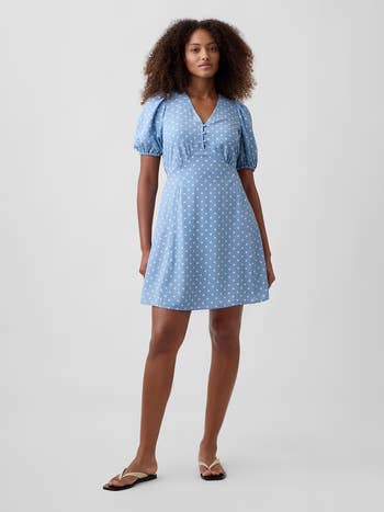 Person wearing a V-neck, puff-sleeve, polka-dot formal and sandals. The mounting is minimal, highlighting the outfit's casual elegance