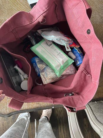 Reviewers pen pink tote bag with various items inside including wipes and cosmetics