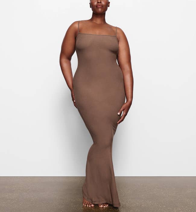 a model wearing the long slip dress in a deep brown color 
