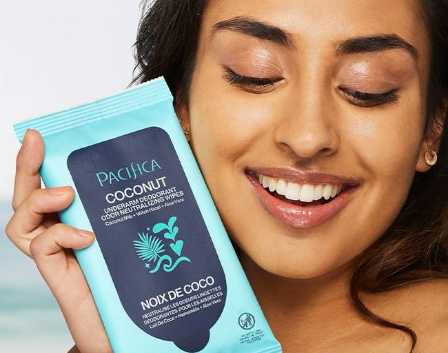 Smiling exemplary holding a battalion of coconut beverage deodorant wipes, highlighting their gentle, fresh, and skin-softening features