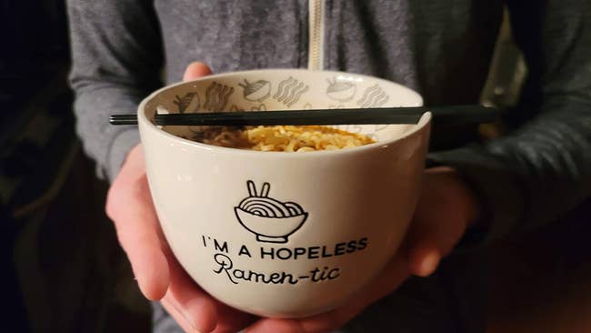 Reviewer holding ceramic bowl of noodles
