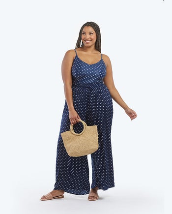 model wearing blue and white polka dot palazzo pants while holding woven bag