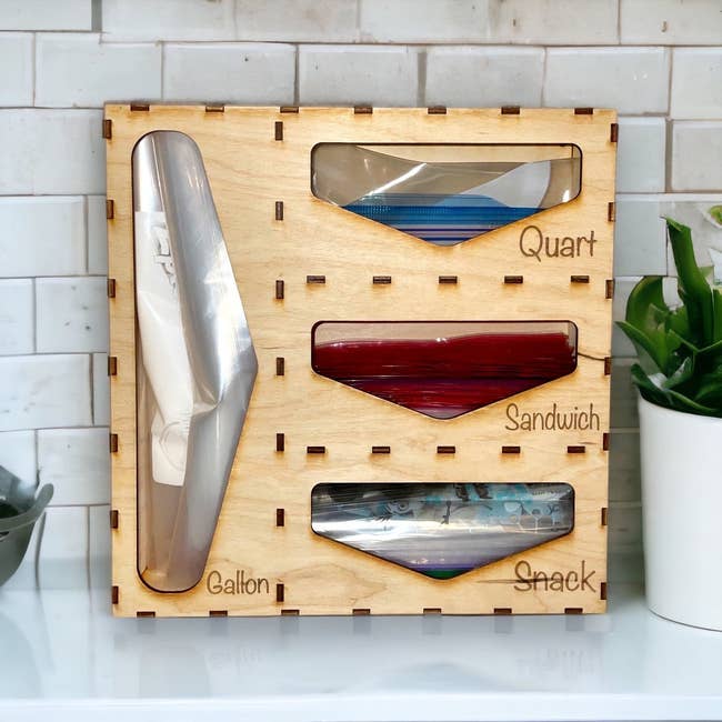 wooden organizer with slots for ziploc bags with the words quart, sandwich, snack, and gallon on it