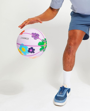 a model dribbling a purple basketball with a floral print 