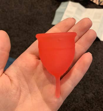 image of the pink menstrual cup in the palm of reviewer's hand