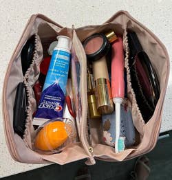 same reviewer's open cosmetic bag with various makeup and skincare products inside