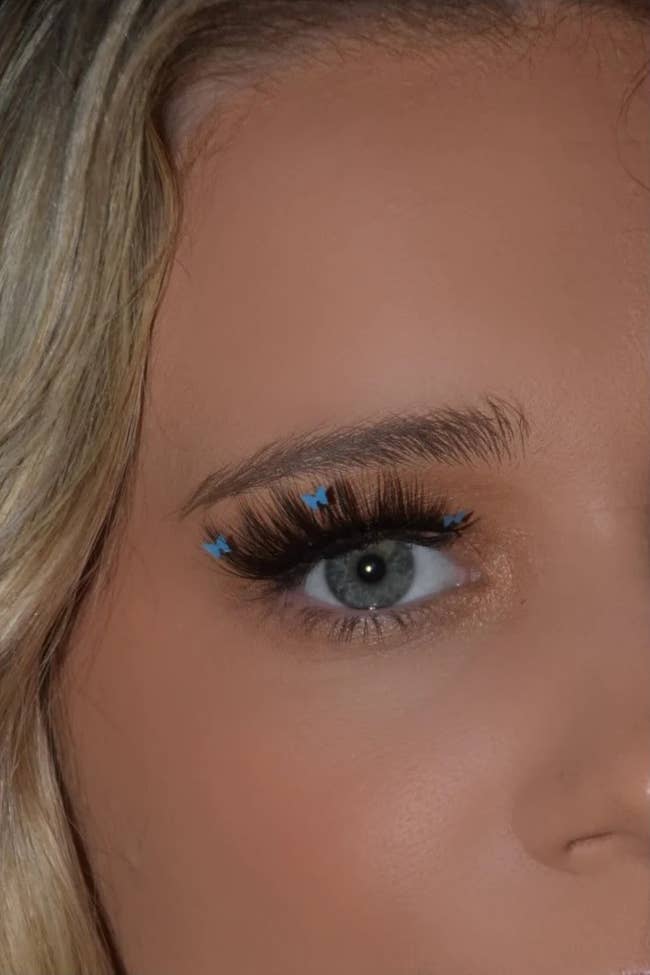 Model wearing lashes with blue butterfly decals attached