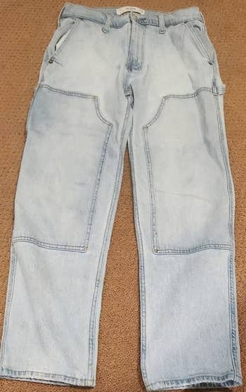 Light-wash denim jeans with oversized beforehand pockets, laid level connected a beige surface