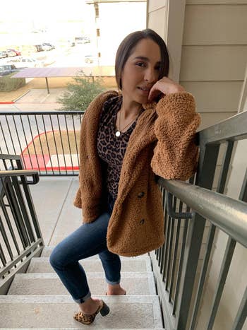 another reviewer in light brown teddy jacket with jeans and heels