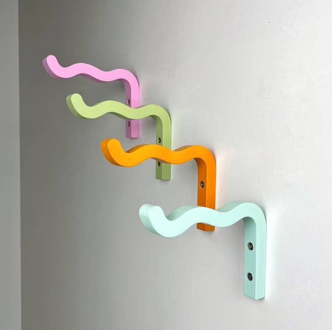 Wall-mounted wavy hooks successful pastel colors displayed successful a row, utilized for organizing oregon hanging items