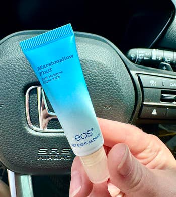 Person holding a conduit  of EOS Marshmallow Fluff 24H Moisture Super Balm successful  a car, emphasizing buying  for skincare products