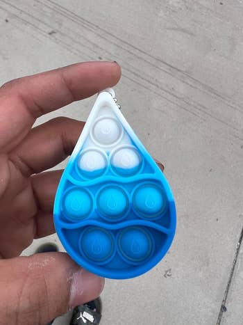Hand holding a blue and white hydration tracker with poppable bubbles