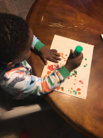Child using stamps to create art on paper at a table, engaged in a creative activity. Perfect for crafting supplies shopping