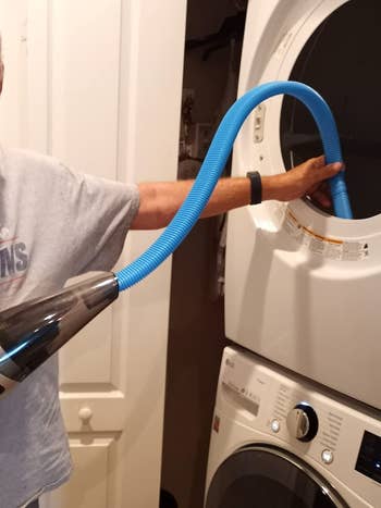 image of reviewer using the hose attachment to vacuum lint out of dryer vent