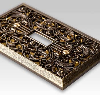 close up of the brass wallplate cover showing the filigree detail