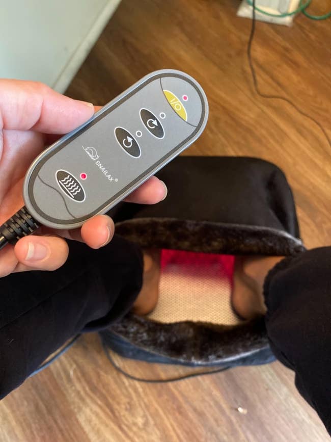 reviewer holding remote with their feet in the massager