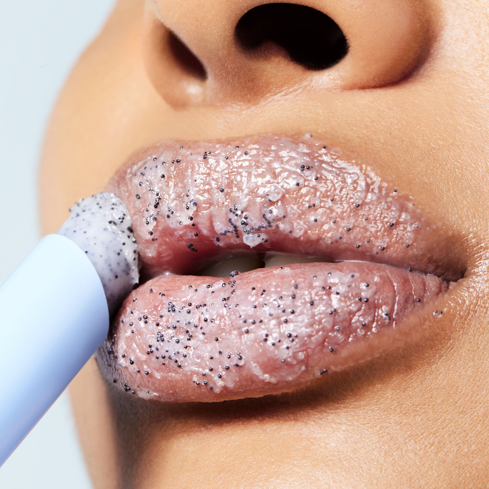 model applying cookies and cream inspired exfoliant in lipstick-like tube
