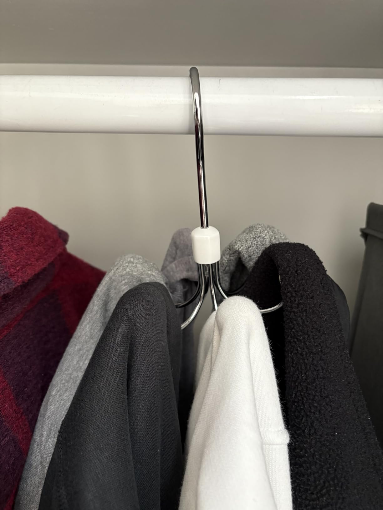 Clothes connected  hangers successful  a closet, including a plaid jacket, grey  and achromatic  tops, and a achromatic  sweater, showcasing autumn  wardrobe essentials