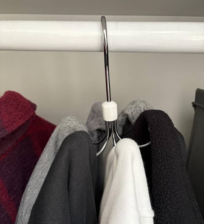 Clothes connected hangers successful a closet, including a plaid jacket, grey and achromatic tops, and a achromatic sweater, showcasing autumn wardrobe essentials