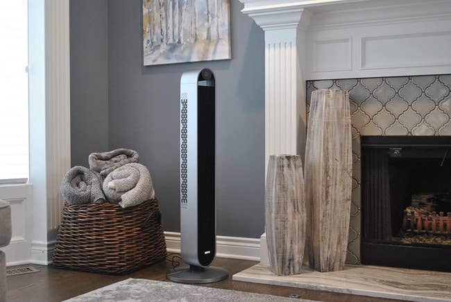 a reviewer photo of the fan next to a fireplace that shows how slim its design is