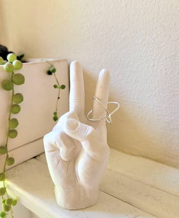 the white stone hand making a peace sign holding a ring