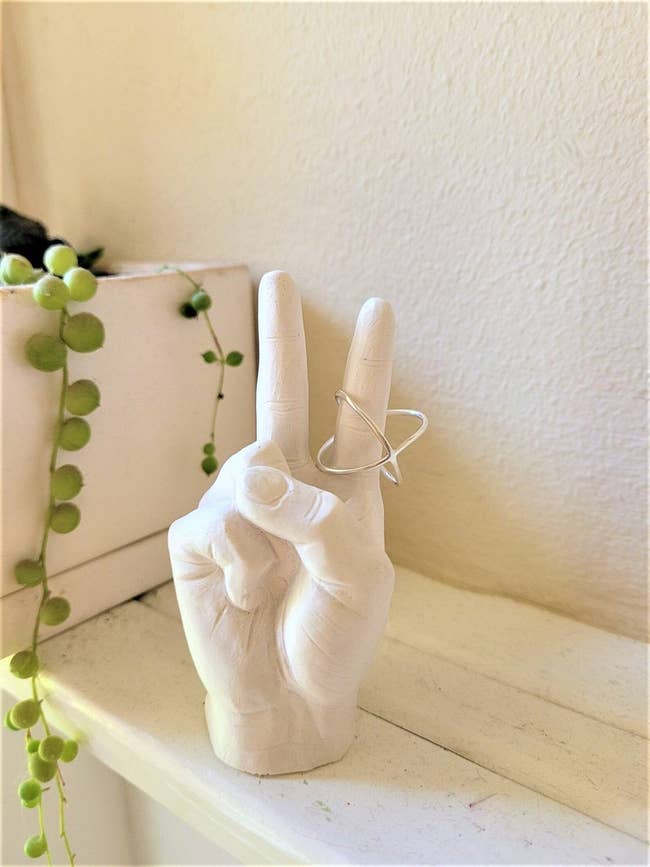 the white stone hand making a peace sign holding a ring