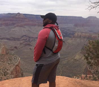 Reviewer pic of them wearing the red hydration pack while staring off into the distance