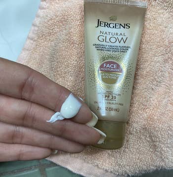 the moisturizer on a reviewer's hand, next to the tube of moisturizer on a towel