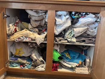 Cabinet overflowing with assorted folded clothing, including shirts and pants, alongside neatly stacked footwear boxes