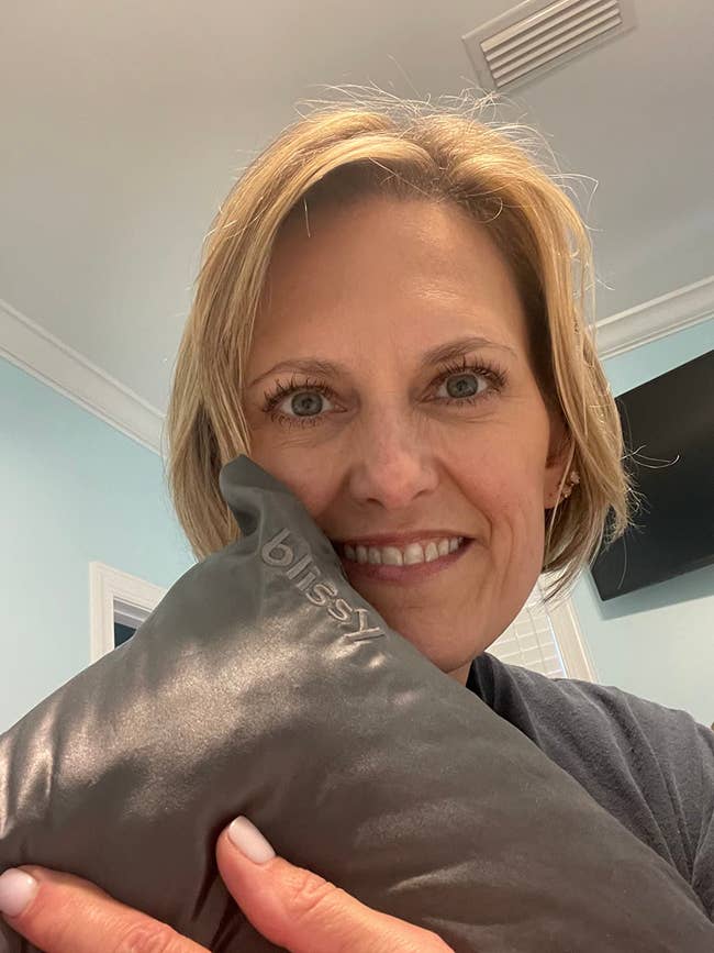 Person smiling portion holding a pillow that has