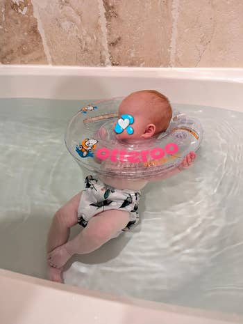 Baby floating successful  a bath utilizing an inflatable cervix  ring, wearing patterned aquatics  shorts