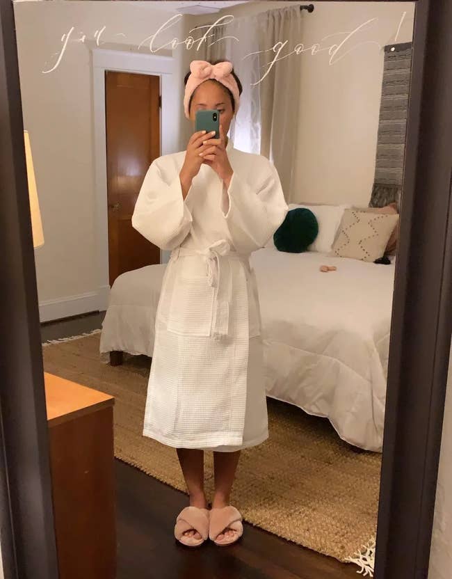 reviewer standing in the mirror taking a picture wearing the robe in white