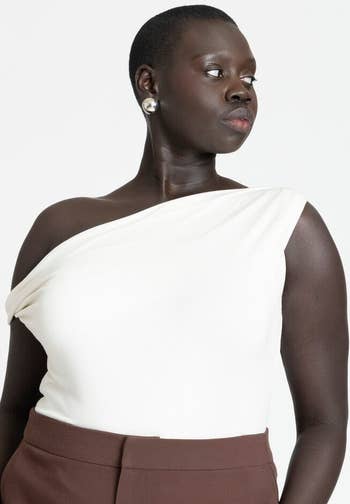 Person wearing a stylish one-shoulder apical  and elegant pants, suitable for a shopping-themed article