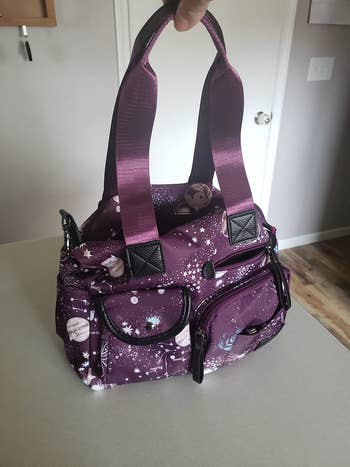 A reviewer holding the bag in a purple color with various space images