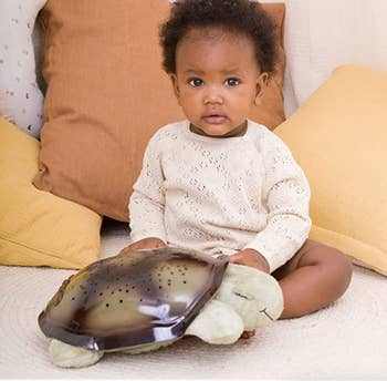 baby holding the hard shell plush turtle doll