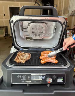 inside the grill with a steak and four sausages