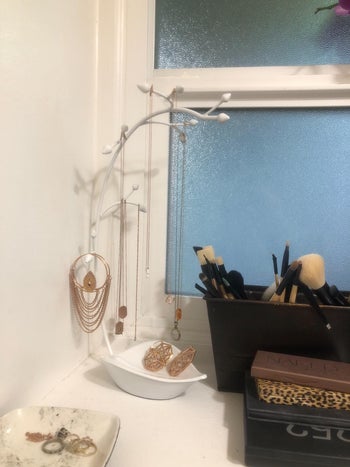 Reviewer image of white tree shaped jewelry holder with necklaces and earrings hanging off it