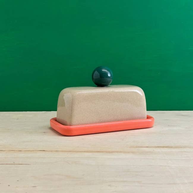 Ceramic food crockery with a rounded handle, acceptable connected a woody surface, against a greenish background
