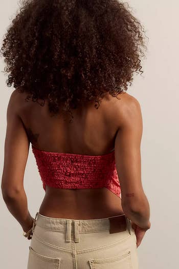 PErson with curly hair wears a textured strapless top with casual pants, seen from the back, showcasing a stylish casual look