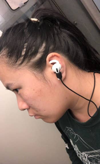 Person wearing black cord attached to AIrPods in their ear 