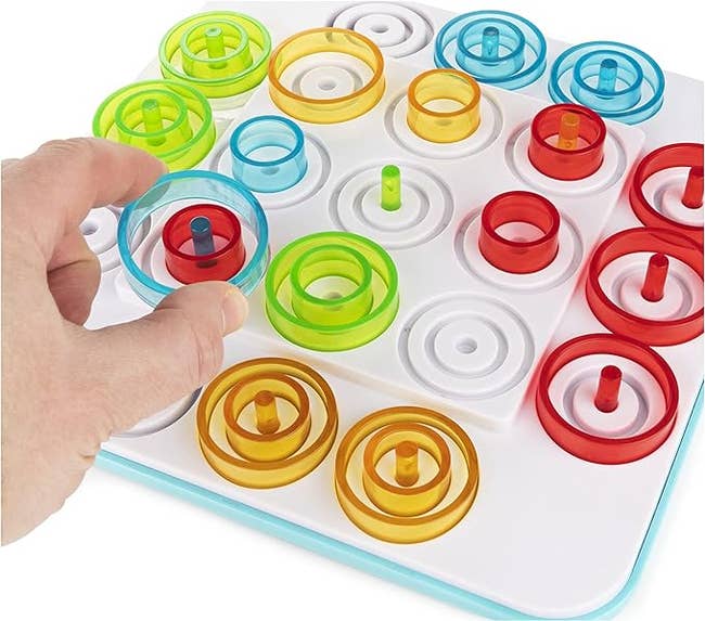 A person placing a plastic ring on the game board
