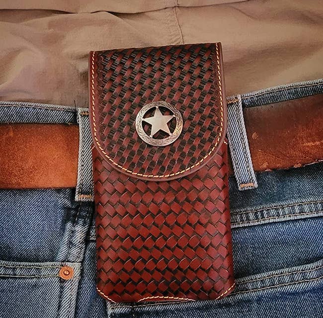 Reviewer wearing slim woven brown leather phone holster attached to brown belt with gold star embellishment 