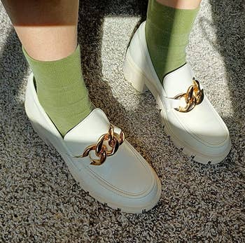 reviewer's feet in the white loafers with green socks