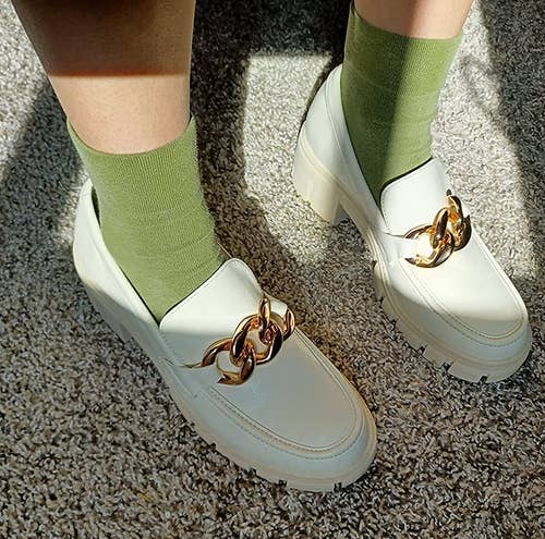 reviewer's feet in the white loafers with green socks