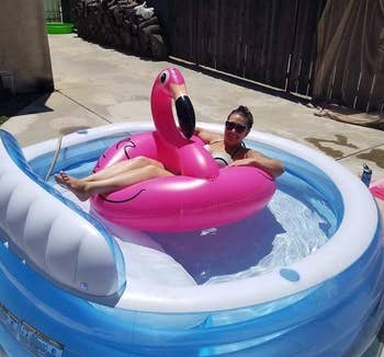 reviewer on a flamingo floatie in an inflatable pool