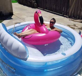 reviewer on a flamingo floatie in an inflatable pool