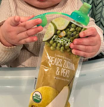 another reviewer's photo of child's hands holding a pouch with green pouch lid attached